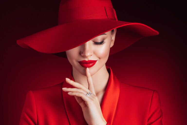 Femme élégante en tenue rouge avec chapeau large, illustrant les codes de l’élégance féminine - élégance féminine - Première Impression